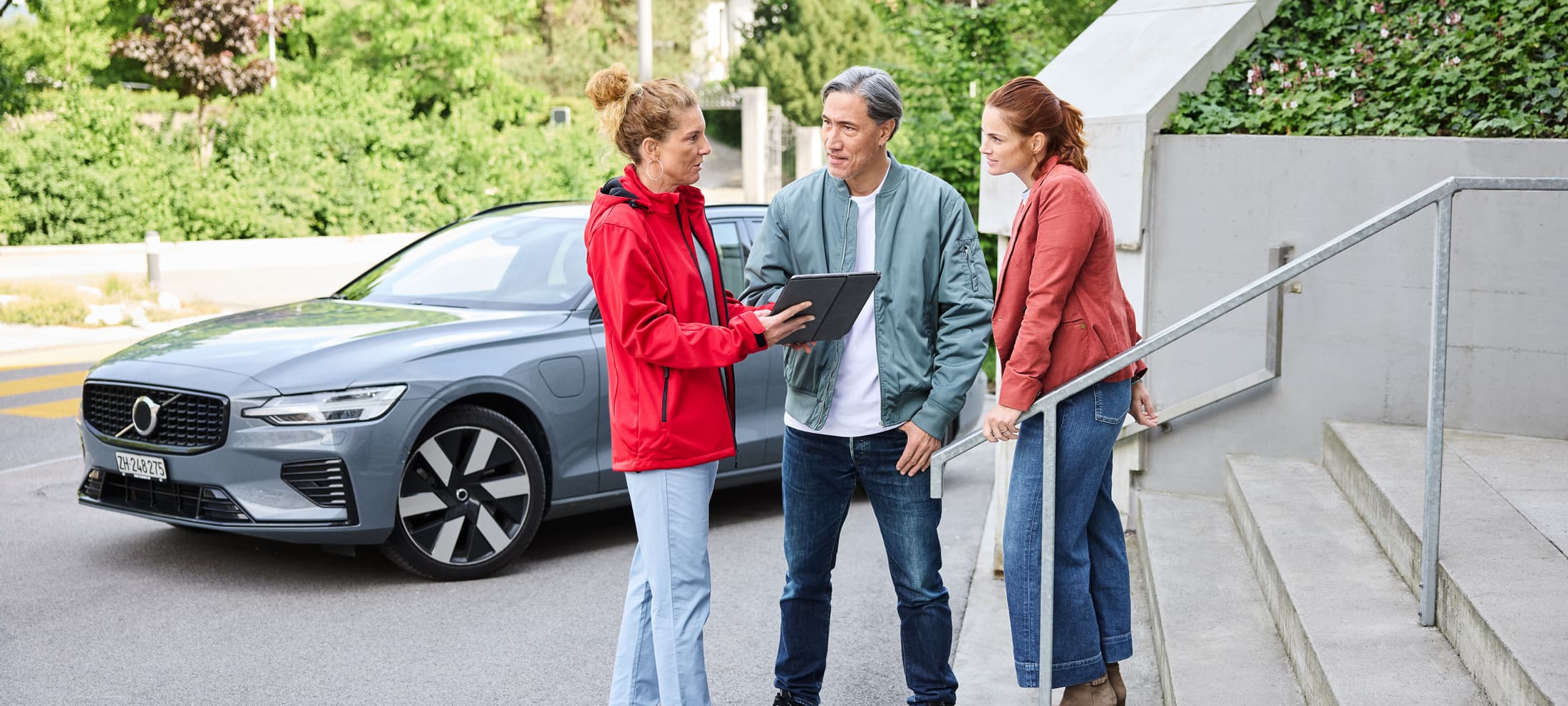 Versicherungsberaterin im Gespräch mit Kunden vor einem Auto