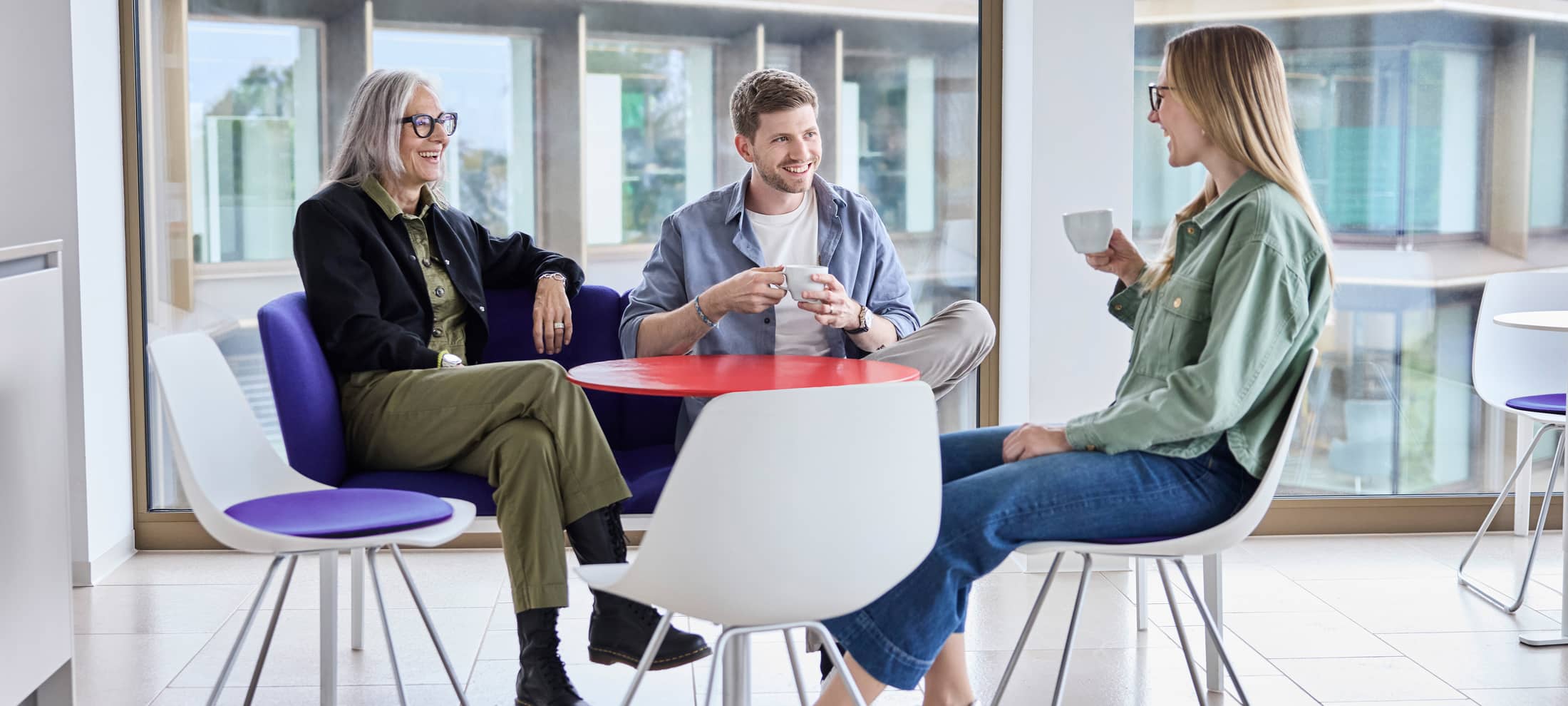 Drei Personen sitzen glücklich zusammen am Tisch