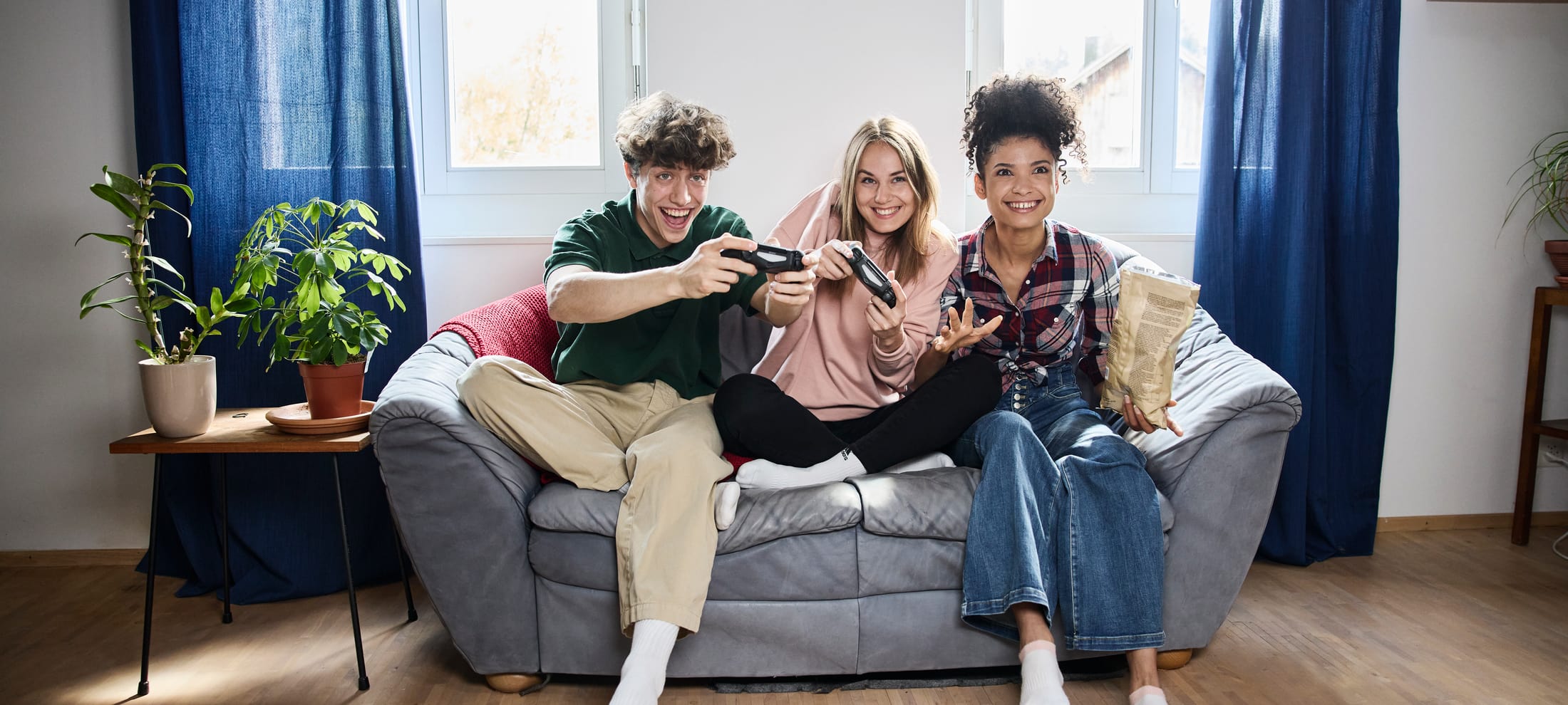 3 Jugendliche sitzen auf einem Sofa und gamen
