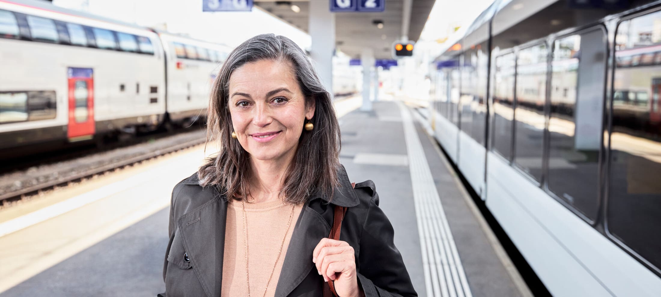 Eine Frau steht auf dem Perron eines Schweizer Bahnhofs und blickt in die Kamera.