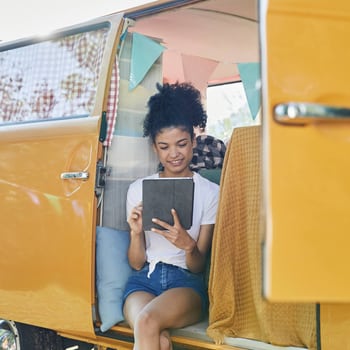 Eine Frau sitzt in ihrem Minibus und schaut schaut auf ihr tablet.