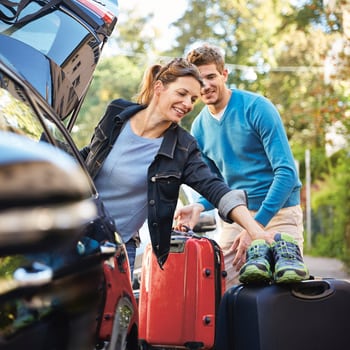 Un couple charge ses bagages dans sa voiture .