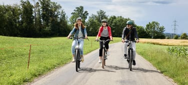 Trois personnes conduisent leur vélo sur une route de campagne