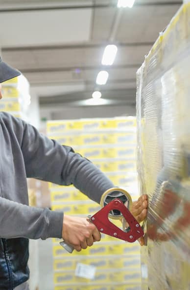 Un addetto al magazzino sigilla la merce su un pallet. 