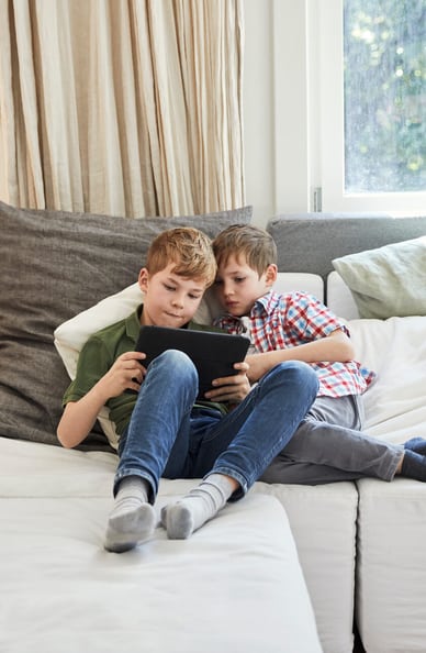 Due fratelli sul divano con un tablet tra le mani 