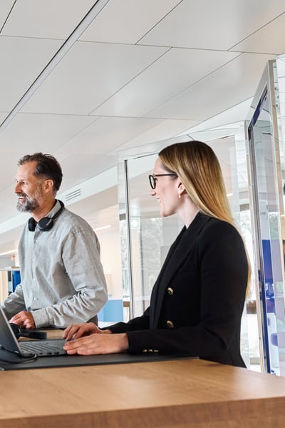 Drei Personen im Büro. Eine Frau erklärt einem Mann etwas und zeigt auf den Bildschirm.