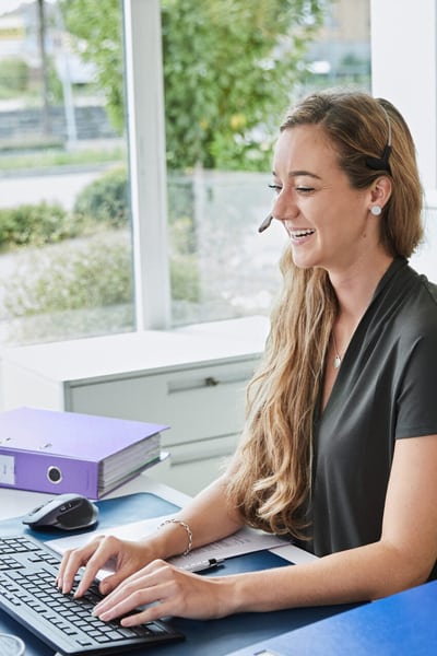 Une jeune femme est assise à son poste de travail devant son ordinateur.