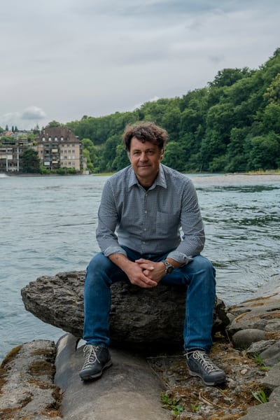 Andreas Zischg, corresponsabile del Laboratorio Mobiliare per la ricerca sui rischi naturali, siede su uno scoglio sulla riva dell’Aare a Berna.
