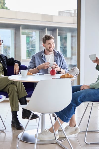 Mitarbeitende unterhalten sich bei Kaffee und Gipfeli