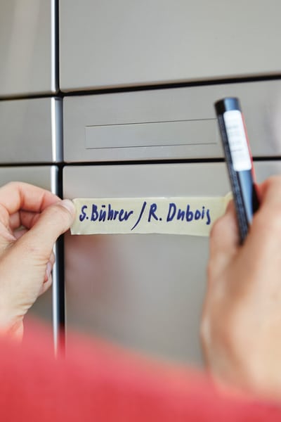 Ein Malerband mit Namen wird am neuen Briefkasten provisorisch befestigt. 