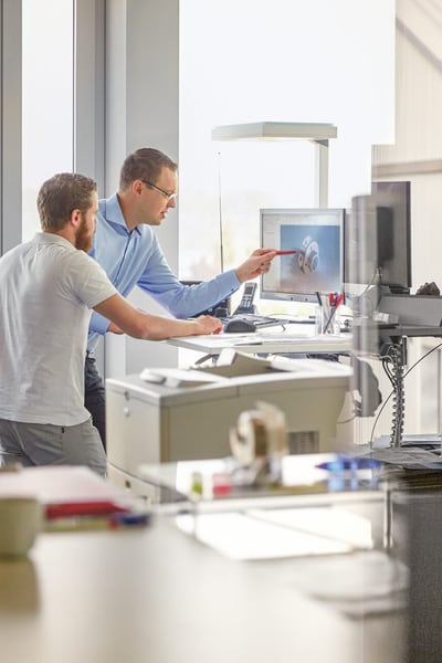 Zwei Männer schauen auf einen Bildschirm.