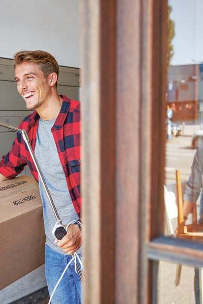 Junger Mann trägt eine Kiste und eine Lampe aus dem alten Haus raus. 