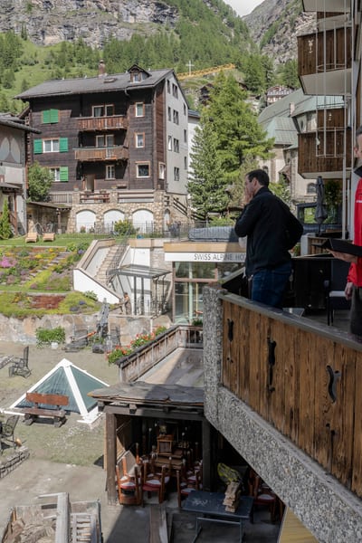 Menschen stehen auf einem Balkon und schauen auf den Schaden, den das Hochwasser in Zermatt 2024 verursacht hat.
