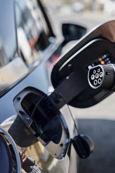 Eine Person ist dabei, den Stecker für das E-Auto in die Buchse am Auto zu stecken.