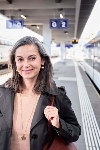 Lächelnde Dame steht auf Bahnsteig neben Zug