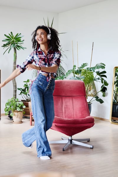 Giovane ragazza ascolta musica con le cuffie e balla nella sua stanza in un appartamento condiviso 