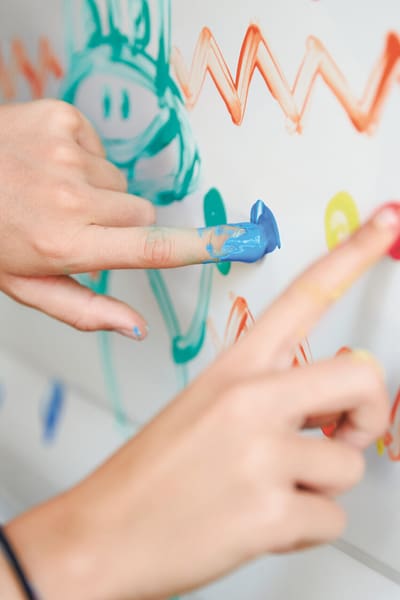 Hände die mit bunten Fingerfarben etwas malen