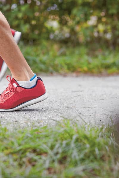 Eine Person joggt in roten Schuhen. Im Bildausschnitt sind nur die Füsse sichtbar. 
