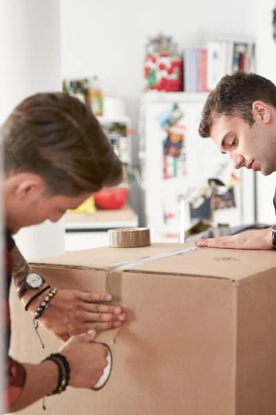 Zwei Männer sind dabei eine Kiste für den Umzug zu packen. 