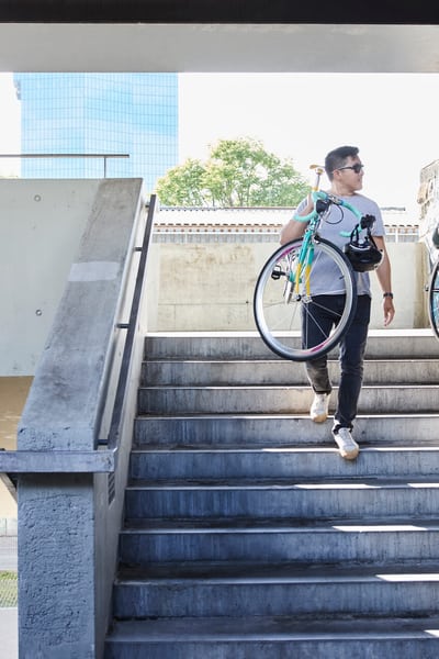 Zwei junge Männer tragen ihre Fahrräder eine Treppe herunter.