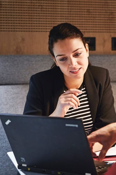 Frau und Mann besprechen etwas und blicken gemeinsam in einen Laptopbildschirm
