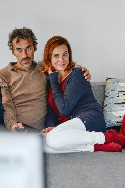 Un couple est assis sur un canapé bras dans le bras.