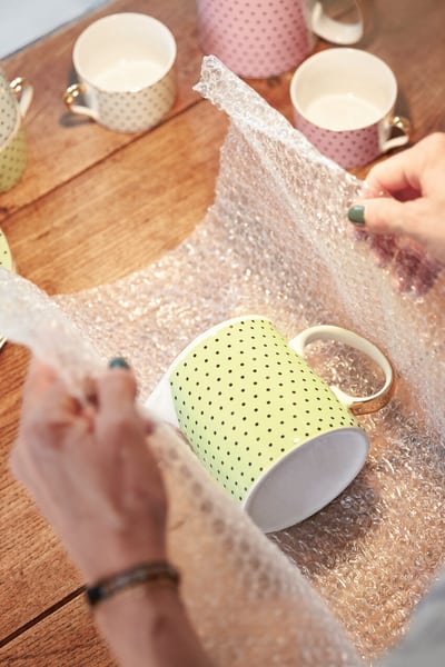 Tasse wird in Luftpolsterfolie verpakt für den Umzug. 