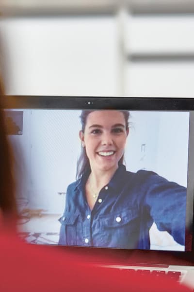unge Frau auf dem Bildschirm eines Laptops, Sie telefoniert gerade per Video-Call mit einer anderen Person.