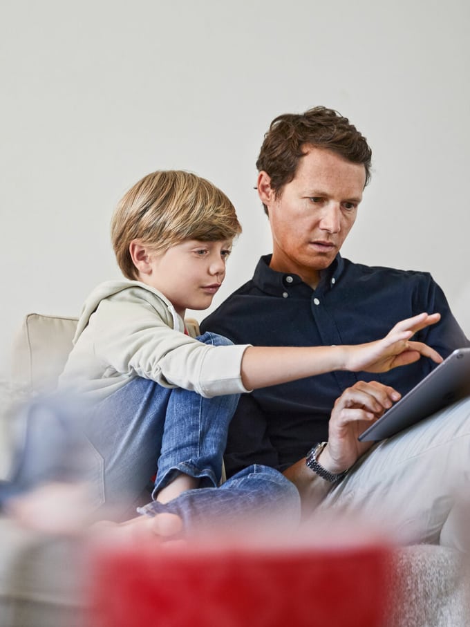 Un père et son fils font du shopping en ligne sur le canapé