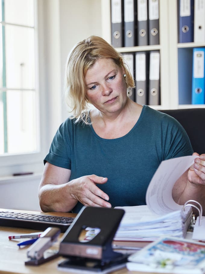 Frau liest Offerten für Ihr Bauprojekt in einem Ordner.