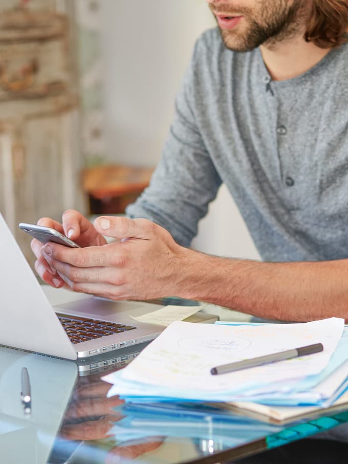 Un uomo lavora con laptop e smartphone
