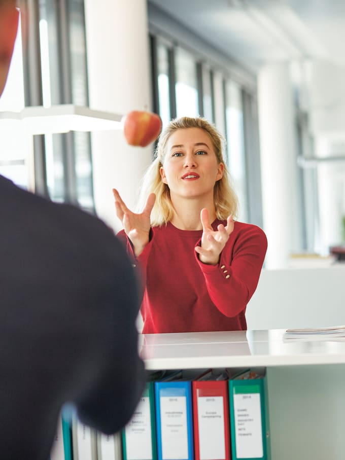 Femme attrapant une pomme au bureau