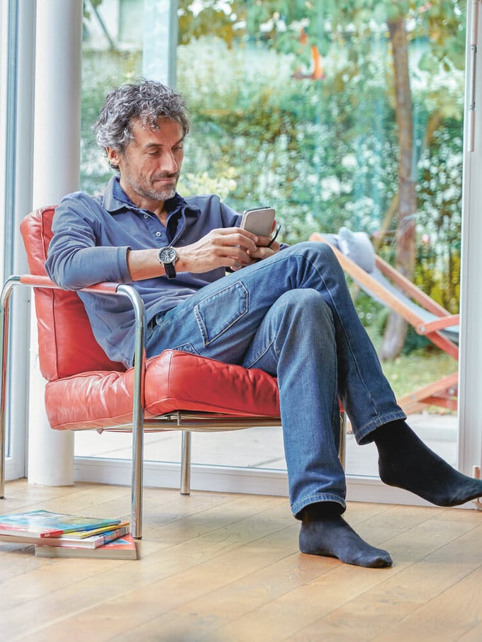 Mann sitzt mit dem Smartphone auf dem Sessel und macht ein Backup.