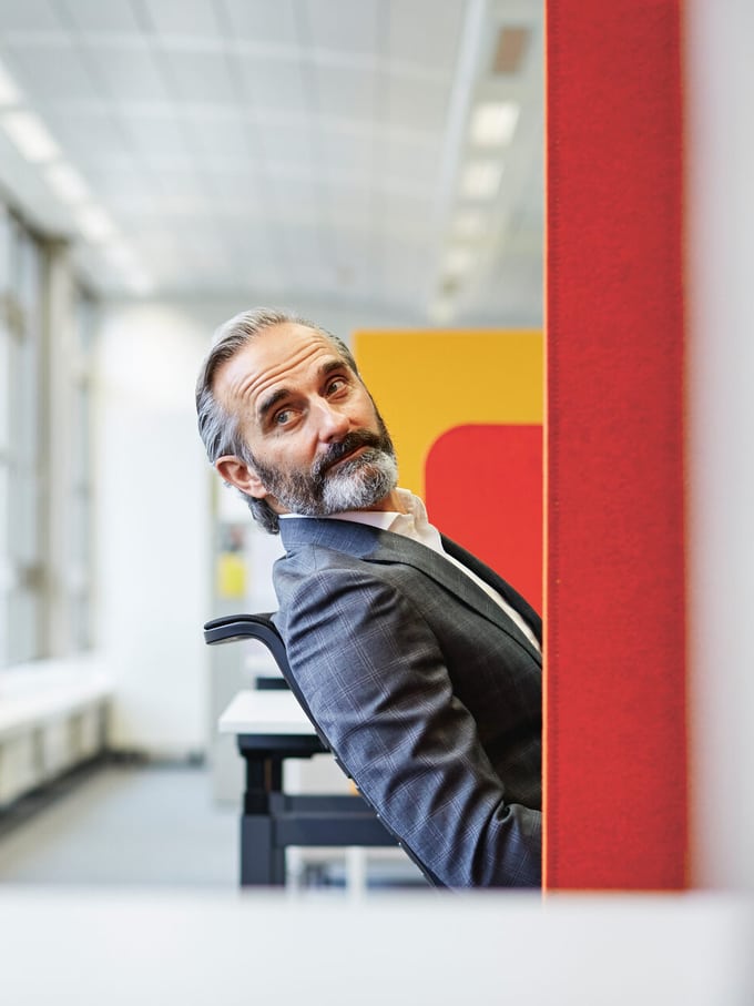 Ein Mann in einem Büro sitzt und schaut nach hinten.