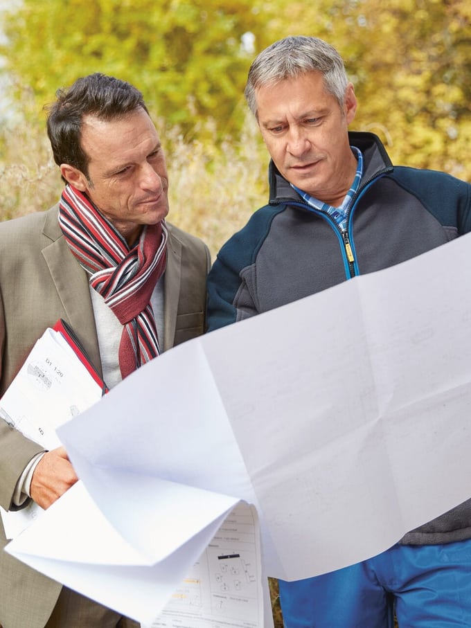 Deux hommes inspectent un plan de construction