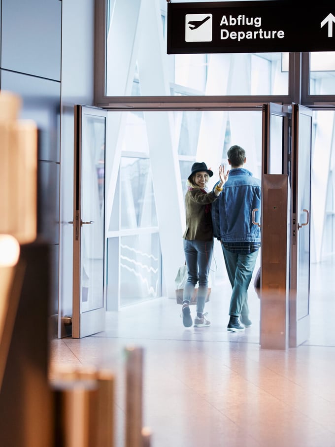 Un jeune couple fait un signe d’adieu dans le hall d’embarquement de l’aéroport de Zurich-Kloten