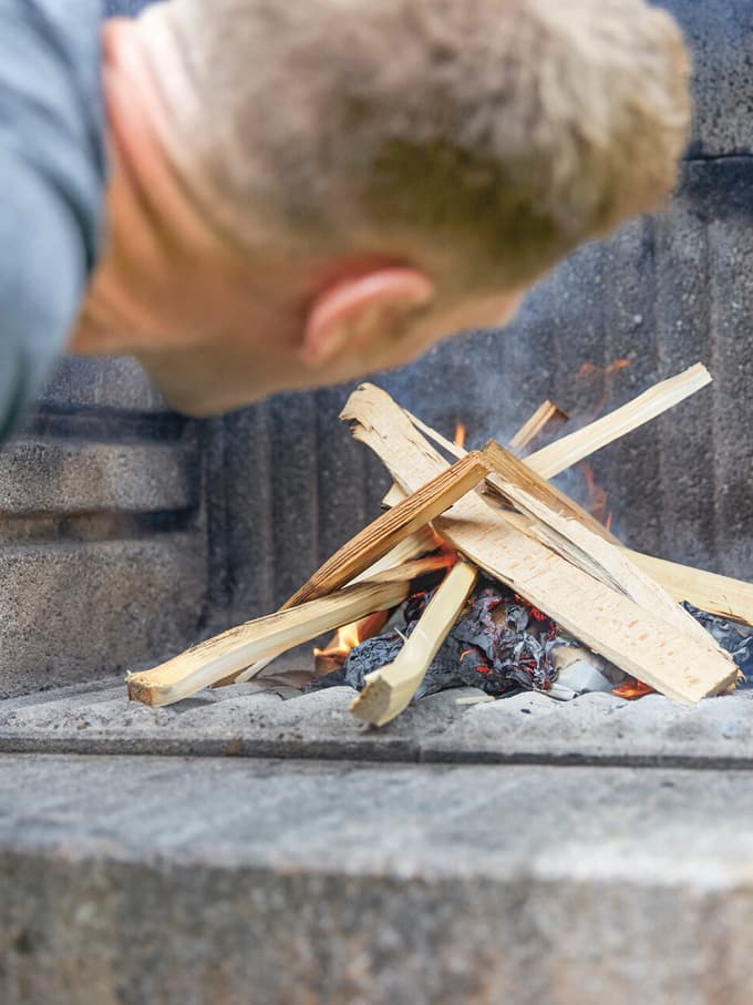 Immagine che simboleggia il disturbo olfattivo: alcuni pezzi di legno sono disposti uno sopra l'altro in modo incrociato e un uomo sta per dargli fuoco.