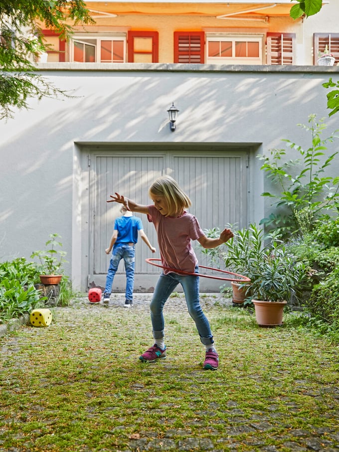 Due bambini giocano in un cortile.