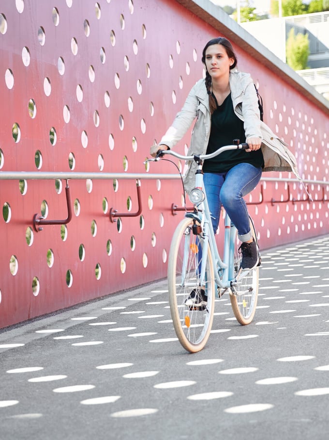 Eine Frau am Velofahren auf einer Brücke in der Stadt