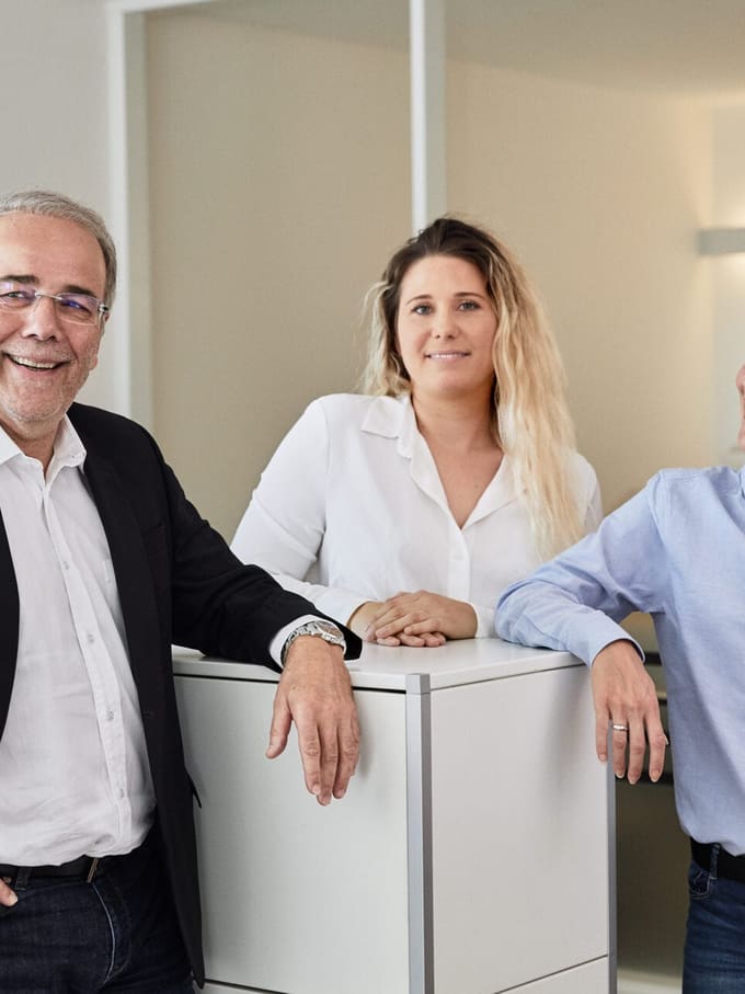 Un homme âgé et deux dames discutent dans un bureau