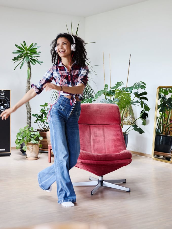 Eine Frau tanzt mit Kopfhörer in ihrer Wohnung.