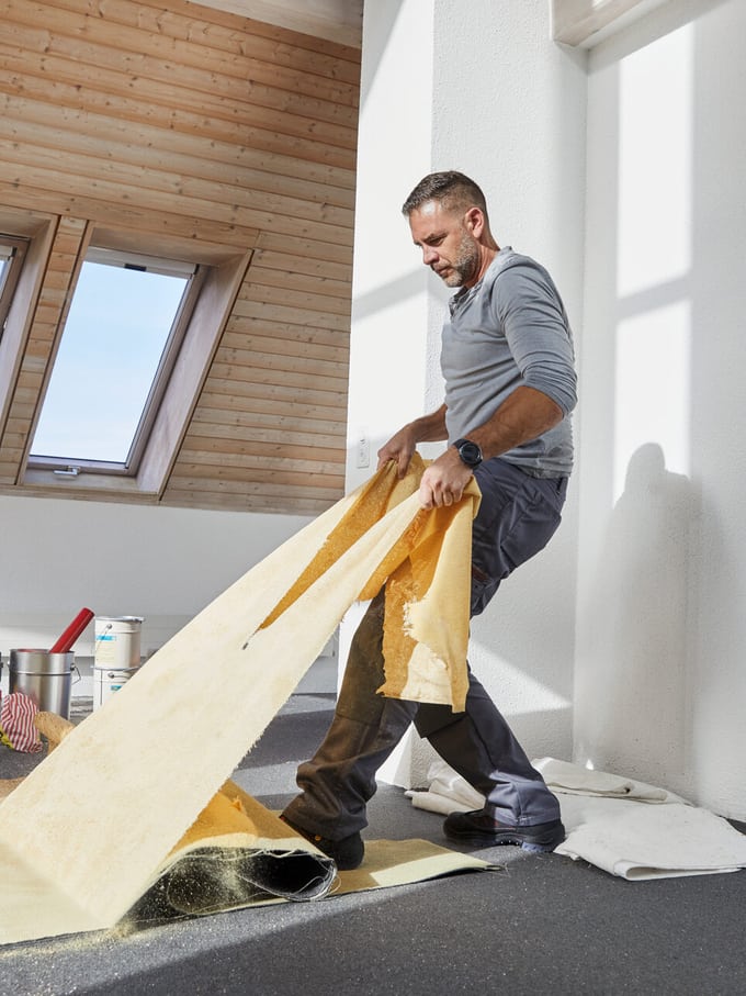 Ein Handwerker reisst einen Boden heraus.