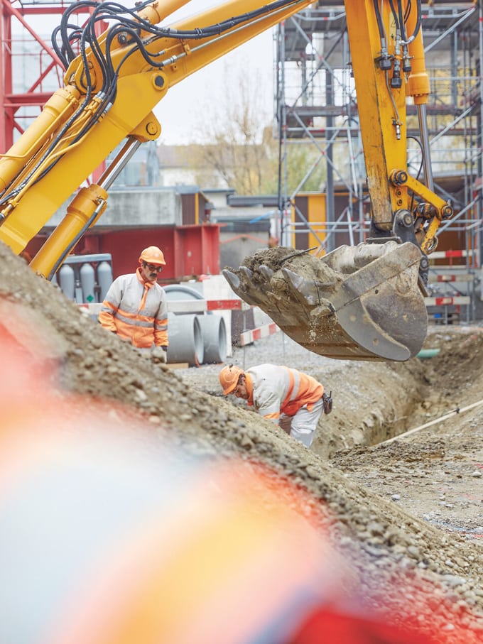 Vue d’un chantier avec un bras de pelleteuse et deux ouvriers, comme symbole de la réduction de loyer pour bruits de chantier