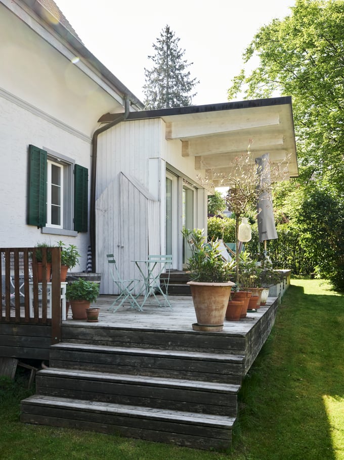 Seitenansicht eines Hauses in grüner Umgebung, Symbolbild für undichte Fenster in einer Mietwohnung in der Schweiz.