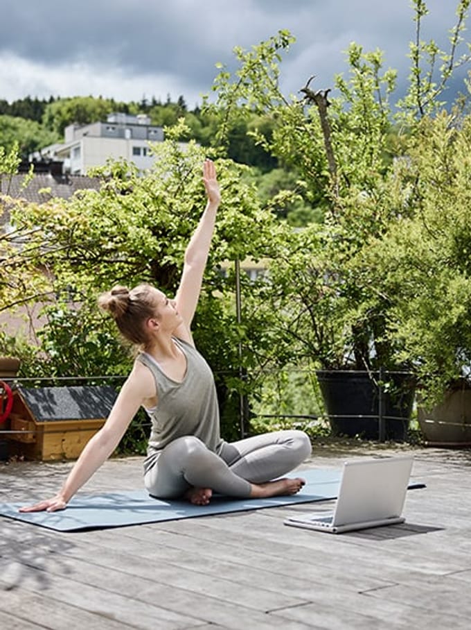 Jeune femme fait du yoga sur une terrasse.