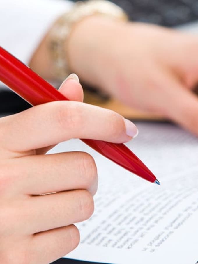 Une personne tenant un dossier et un stylo à la main