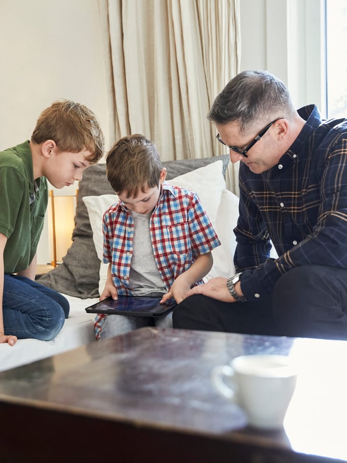 Ein Vater mit zwei Kindern am Tablet