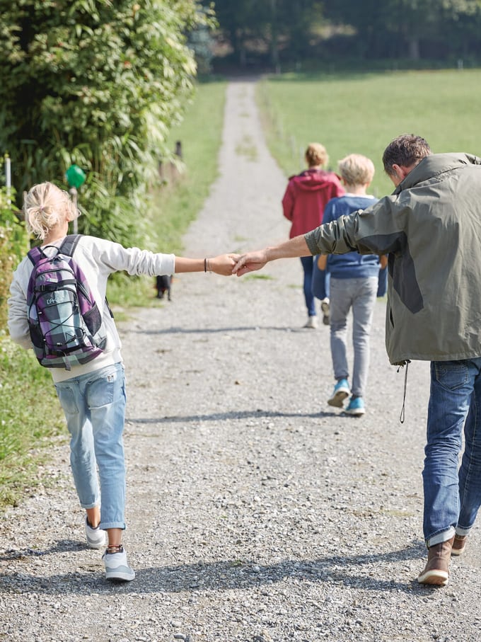 Una passeggiata in famiglia su una lunga strada sterrata. Padre e figlia si tengono per mano come immagine simbolica del mandato precauzionale.