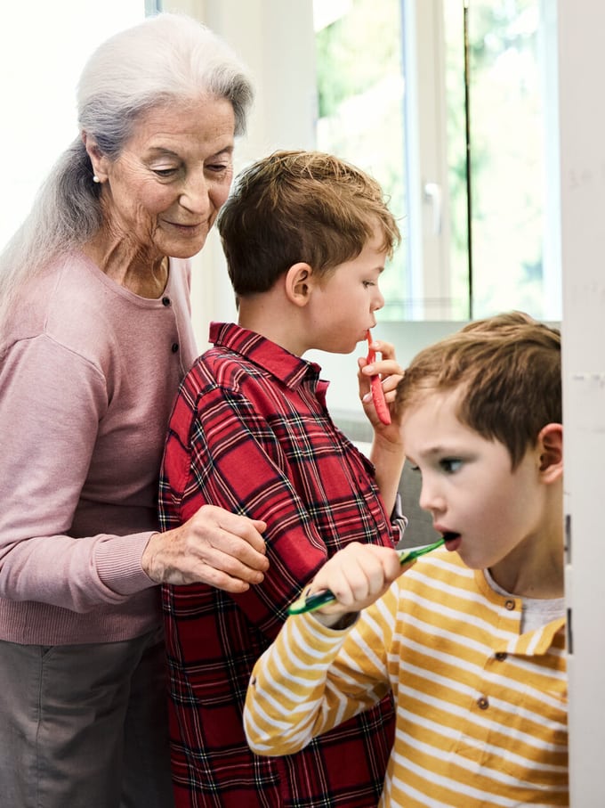Image symbolisant l’avancement d’hoirie: une grand-mère attentionnée aide ses petits-enfants à se brosser les dents.