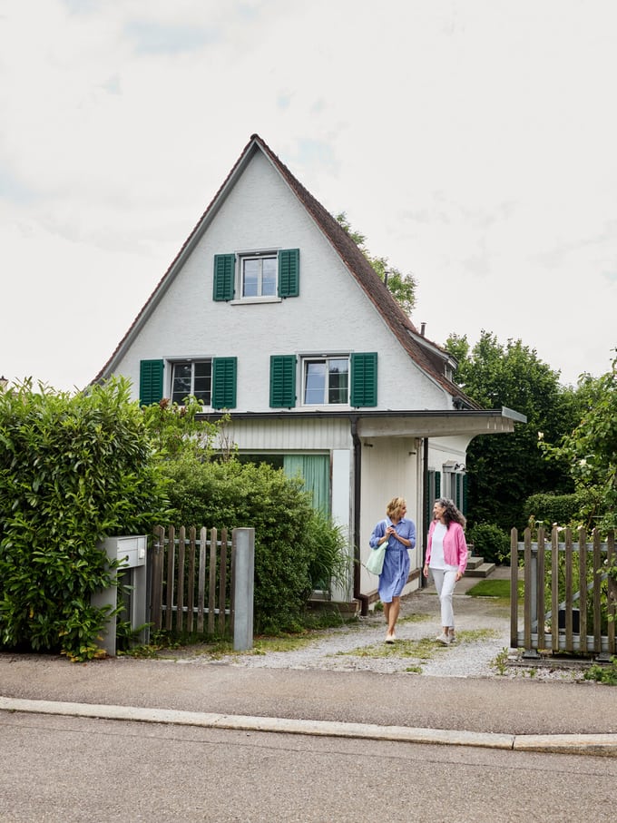 Haus mit zwei Personen im Vorgarten
